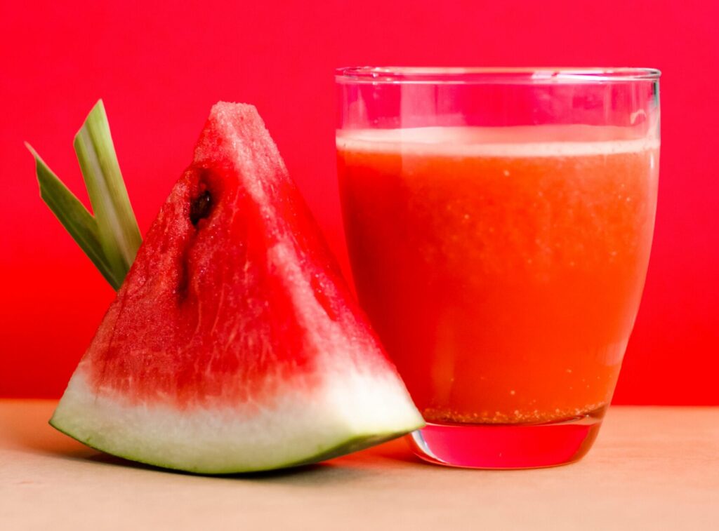 Refreshing watermelon juice and slice against a vibrant red background, perfect for summer vibes.