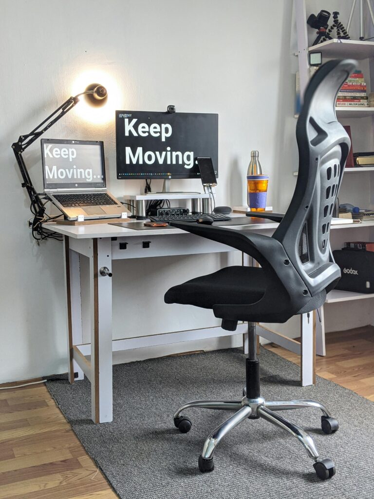 Stylish home office with ergonomic chair, desk, laptop, and motivational screens.